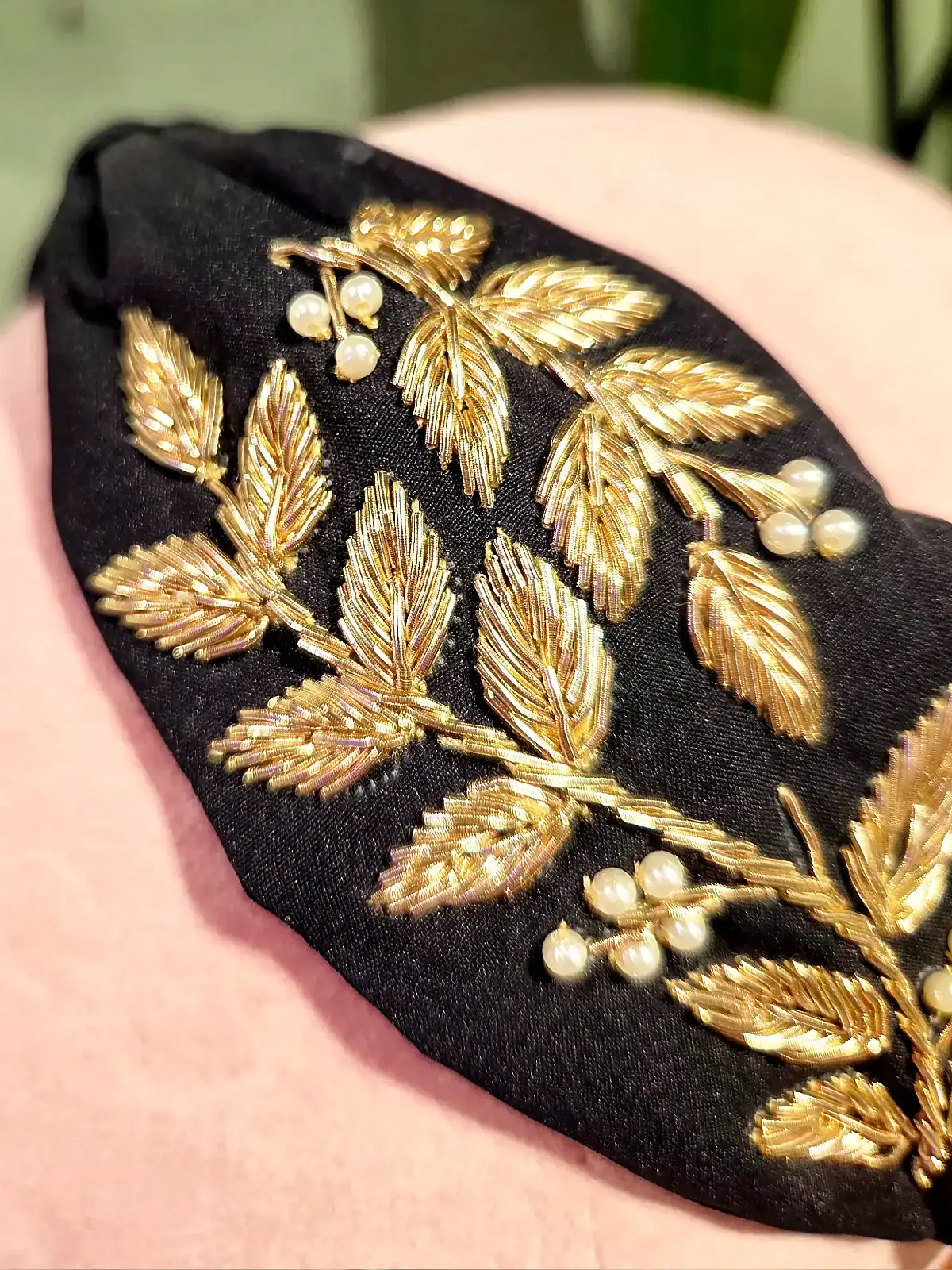 Sort hårbøjle med guld- og perleblomster, perfekt til elegante looks.