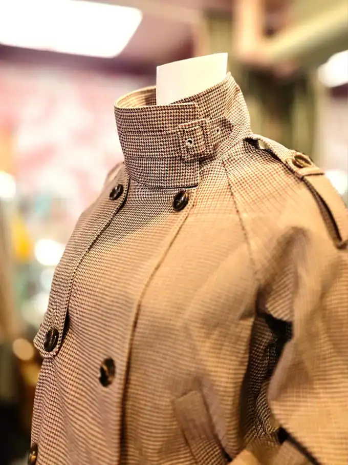 Klassisk beige trenchcoat med knapper og skulderremme.