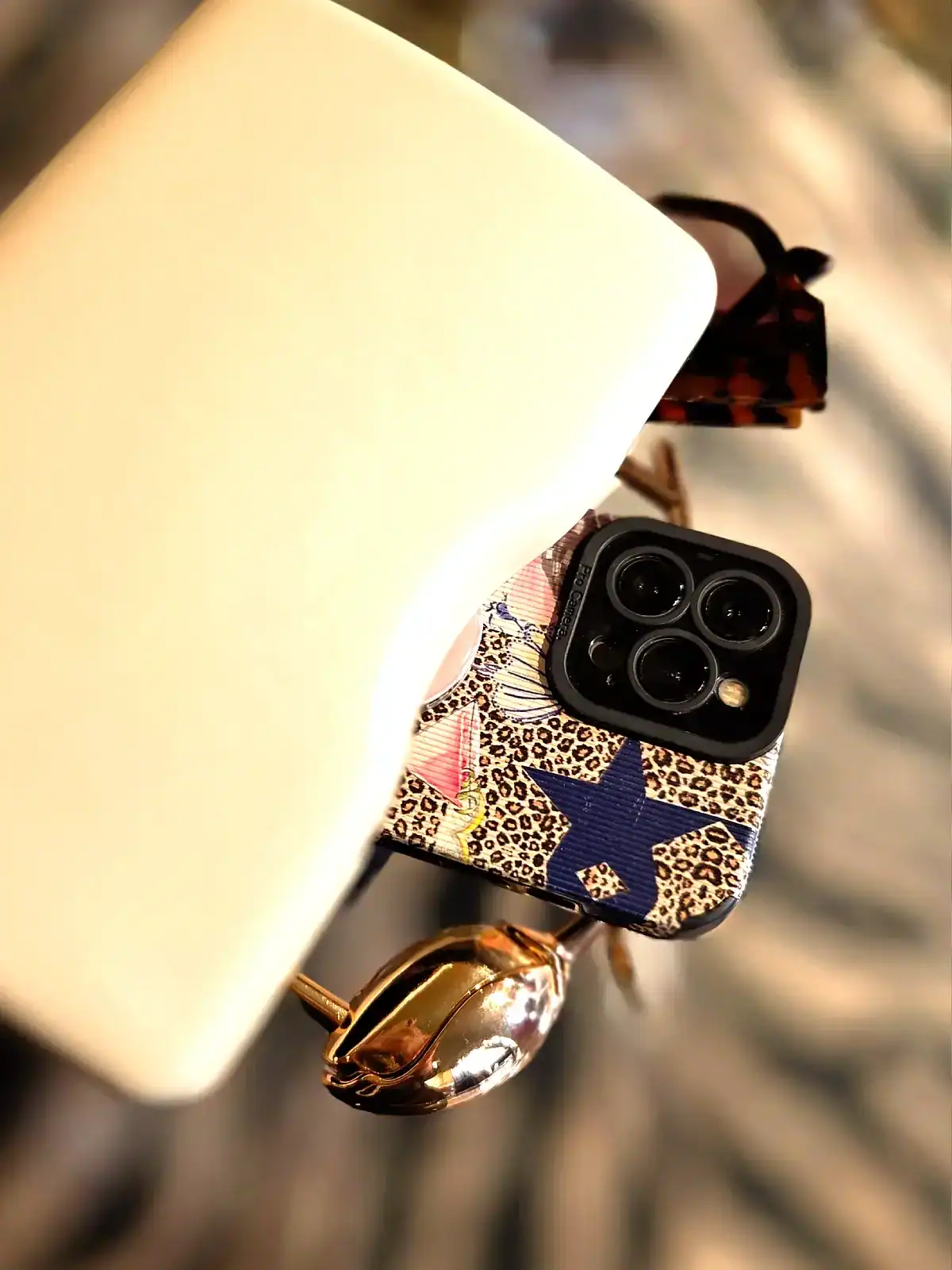 Sort clutch med stjerneprint og smartphone, tilbehør til elegante outfits.