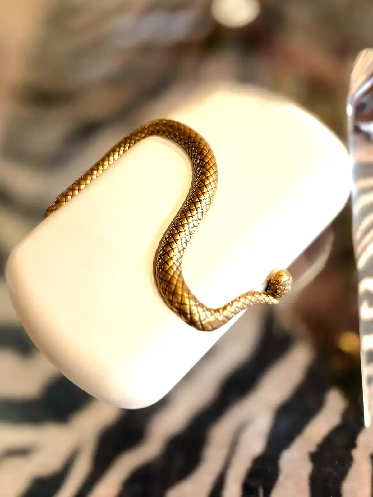 Sort slange clutch med guldfarvet slangehåndtag.