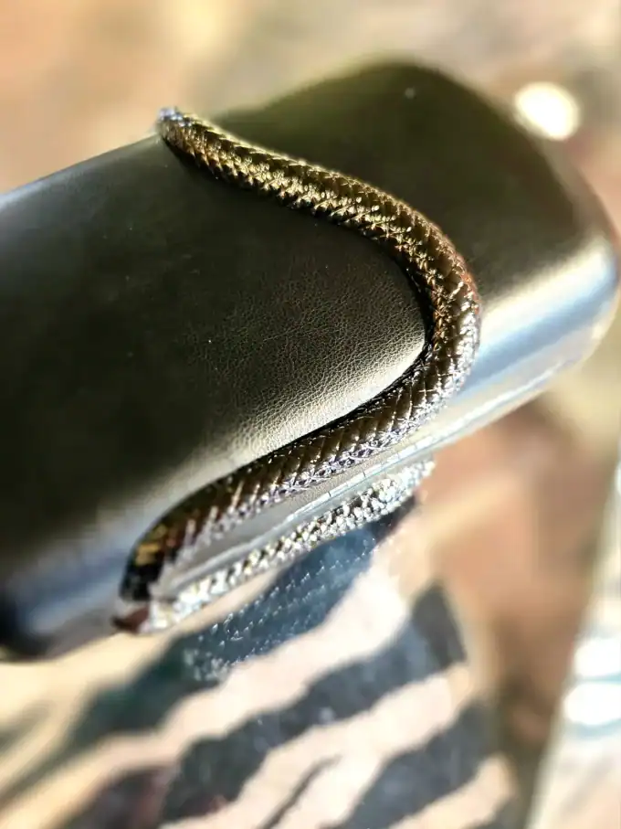 Sort slange clutch med glitrende detaljer, elegant og stilfuld accessory.