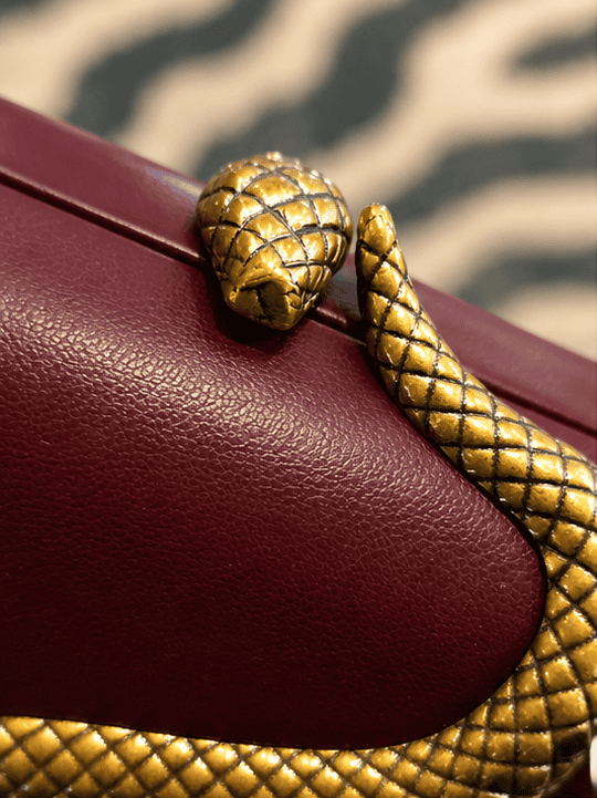 Sort slange clutch med gyldne detaljer og krokodillemønster.